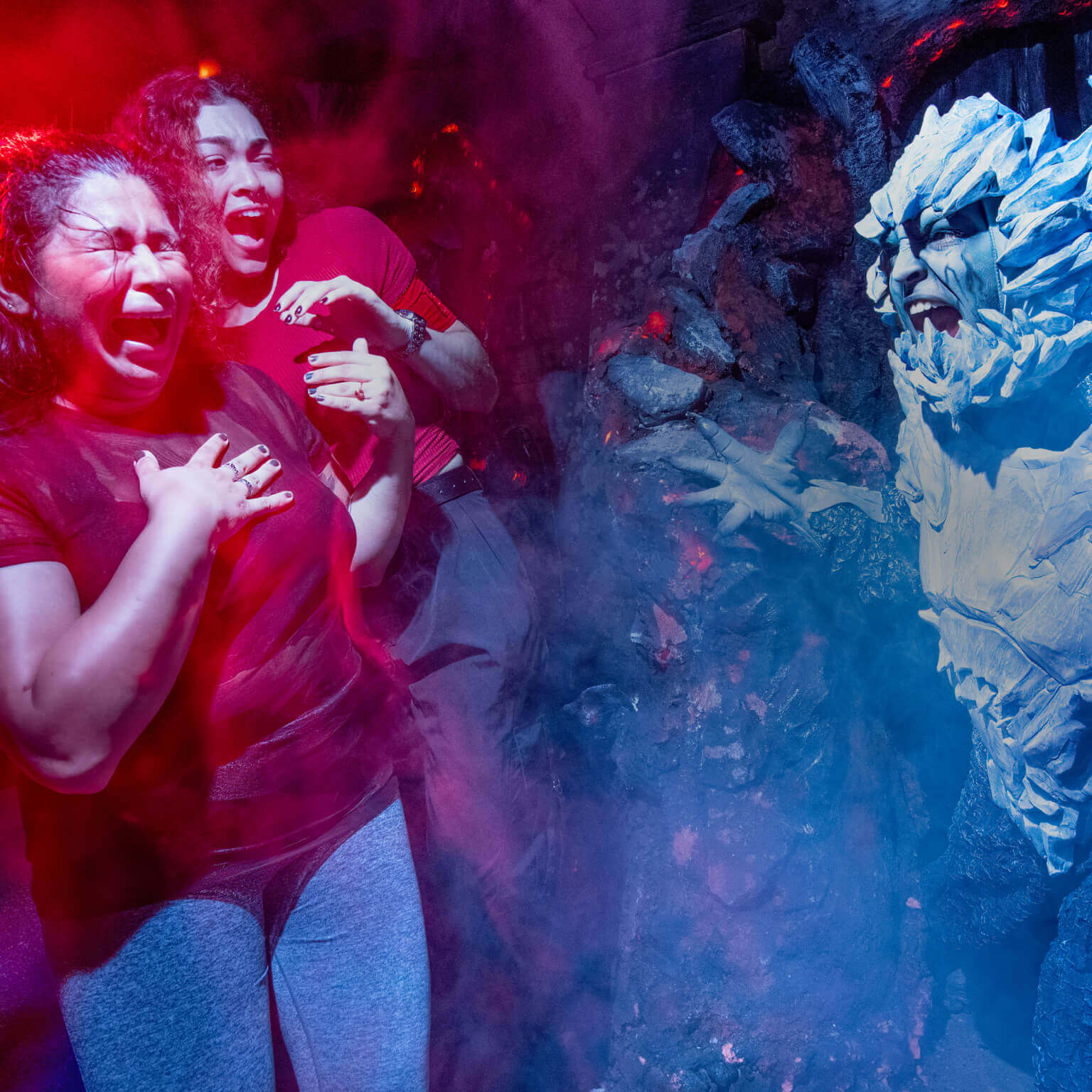 A pale white, horned demon with claws frightens two women in a haunted house