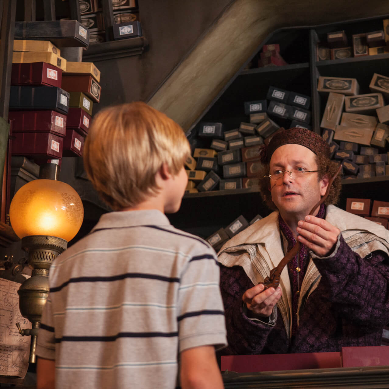 An Ollivanders staff member helping a young boy find the perfect wand inside The Wizarding World of Harry Potter Hogsmeade at Universal's Islands of Adventure.