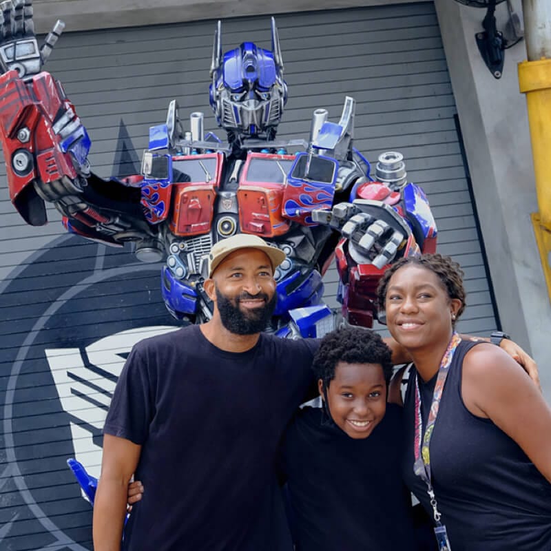 Family smiling in front of Optimus Prime at Universal Studios Florida.