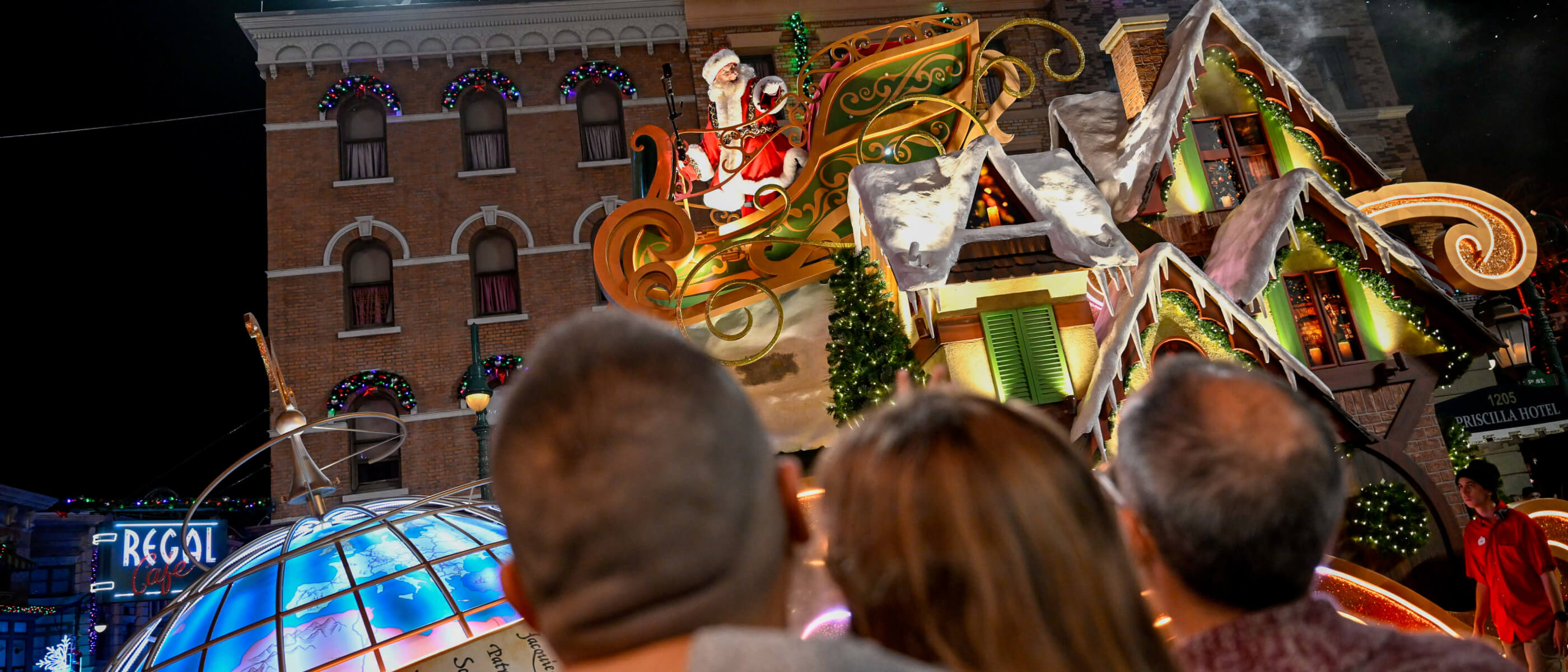 People watching a parade float of Santa in his sleigh on a housetop going by during Holidays at Universal Orlando.