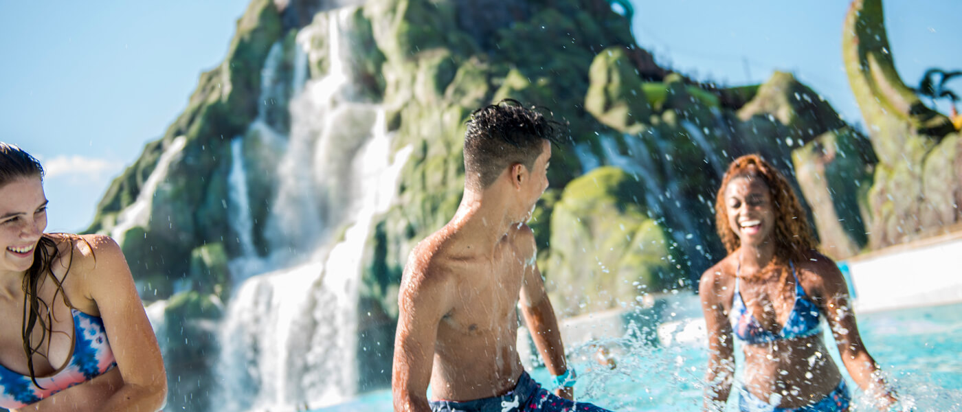 Teenagers splash through the Waturi Beach lagoon at the base of the volcano at Universal’s Volcano Bay water theme park.