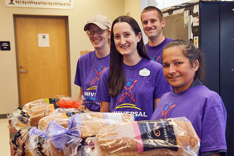 Group of Universal Orlando Volunteers smiling behind loaves of bread.