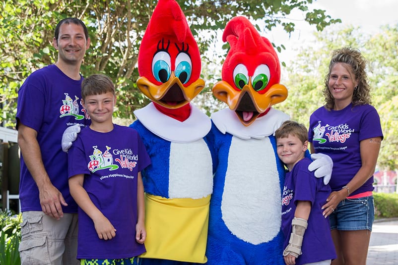 Woody & Winnie Woodpecker posing with a family that is wearing Give Kids The World Village t-shirts.