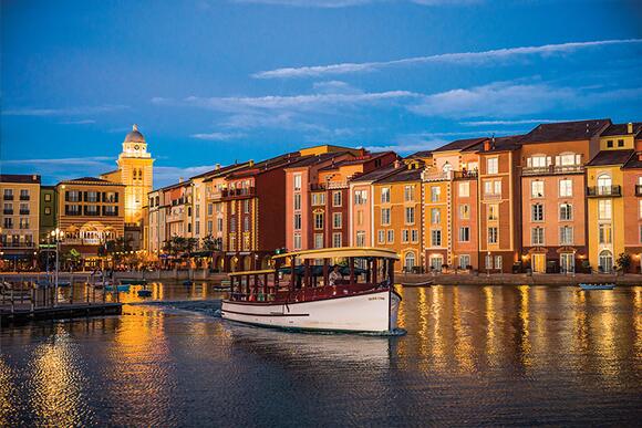 Exterior view of the Itlaian-styled Loews Portofino Bay Hotel at Universal Orlando with a water taxi carrying passengers to CityWalk in the foreground.