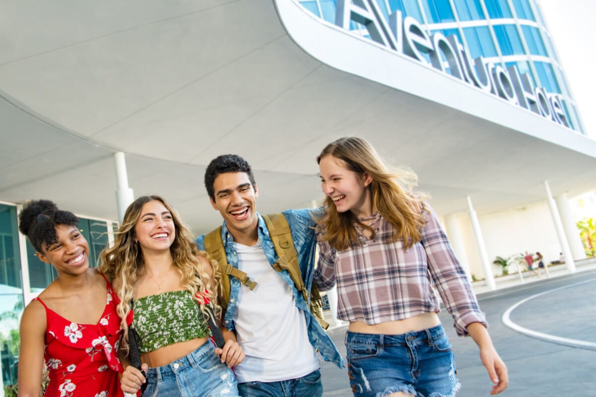 Four friends smiling while walking at the entrance of Universal Aventura Hotel at Universal Orlando Resort.