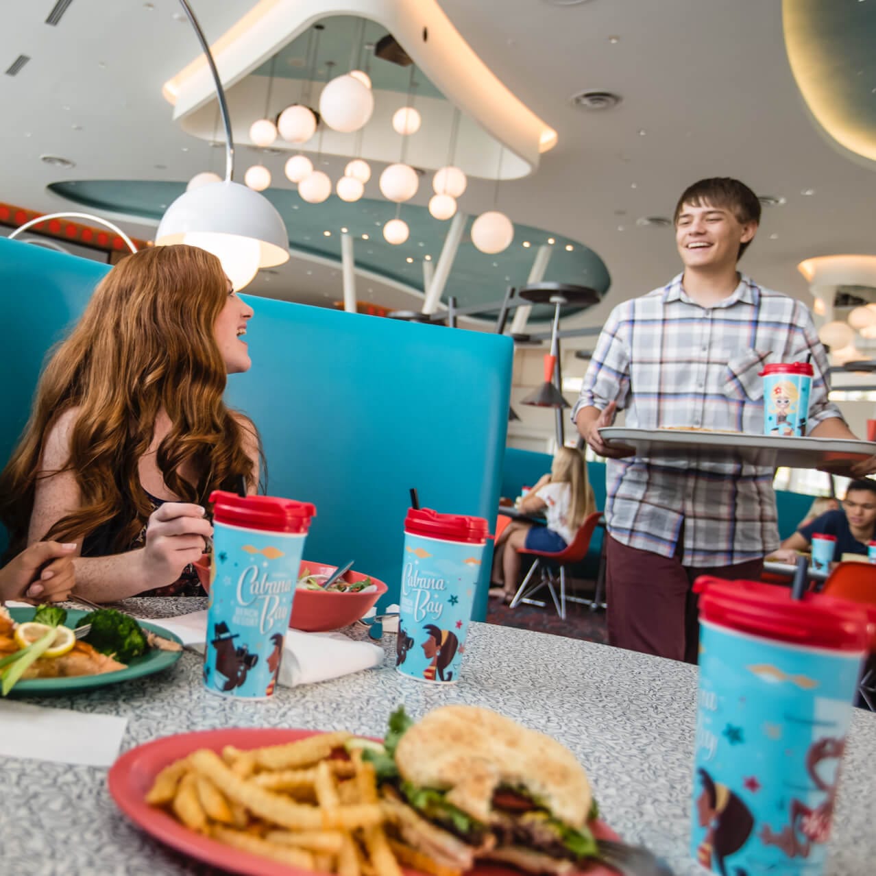 Guests sit down at a blue booth inside the Bayliner Diner at Universal's Cabana Bay Beach Resort.
