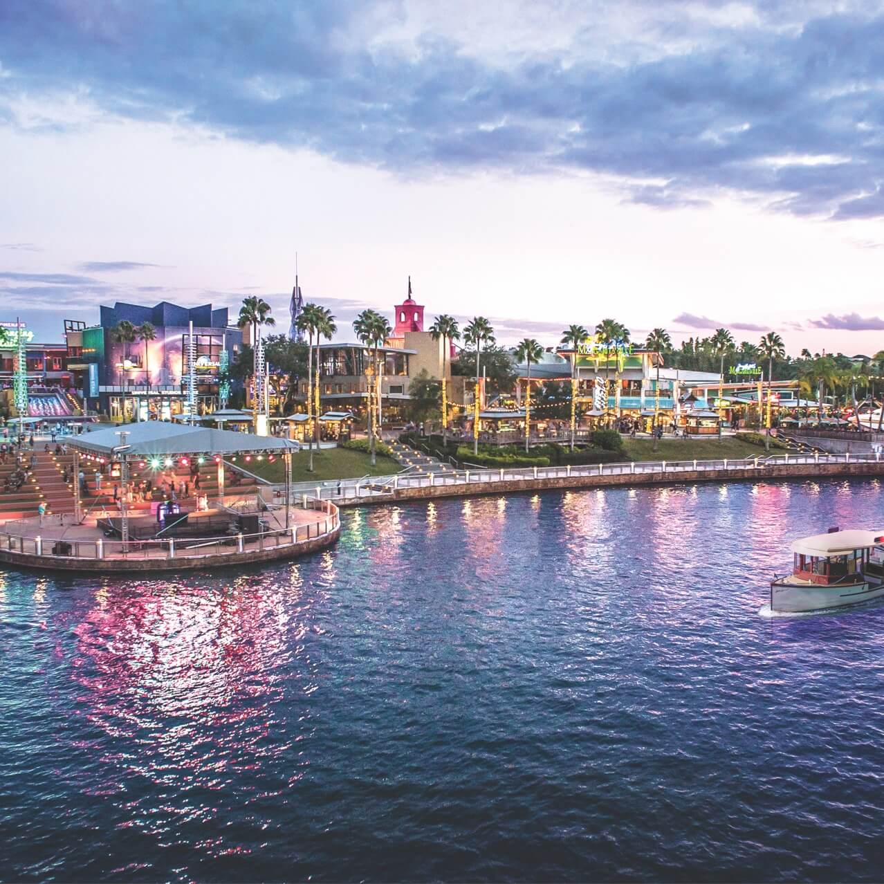 A water taxi cruises along the lagoon in front of a panoramic view of the restaurants, shops and nightclubs of the Universal CityWalk entertainment complex.