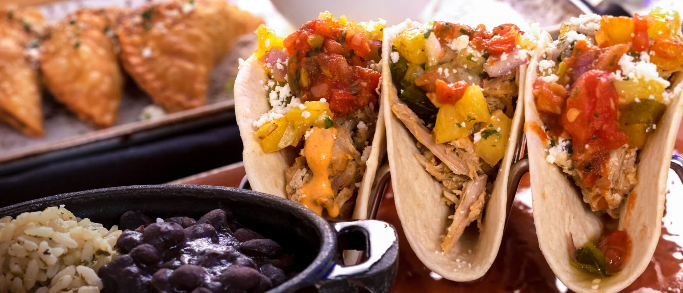 Fresh tacos beside a bowl of black beans at Antojitos Authentic Mexican Food restaurant in Universal CityWalk.