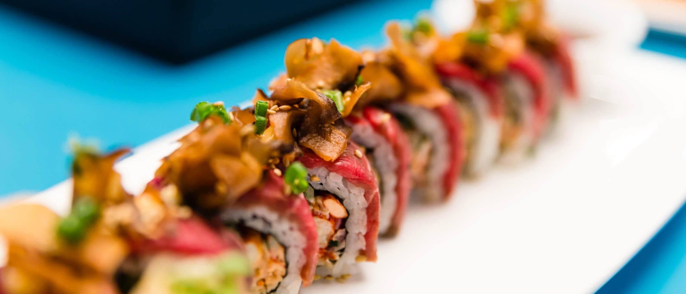 A line of fresh tuna topped sushi plated at Universal CityWalk's Cowfish Sushi Burger Bar.