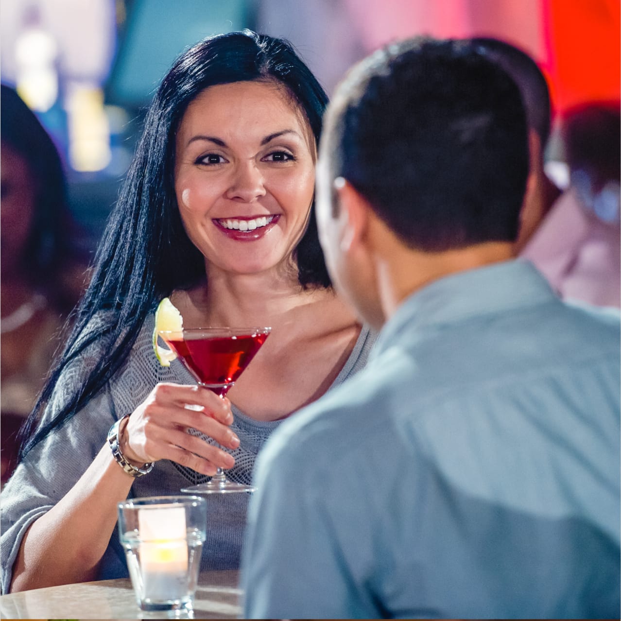 A woman holds a martini and smiles across the table at a friend inside Universal CityWalk's Red Coconut Club.