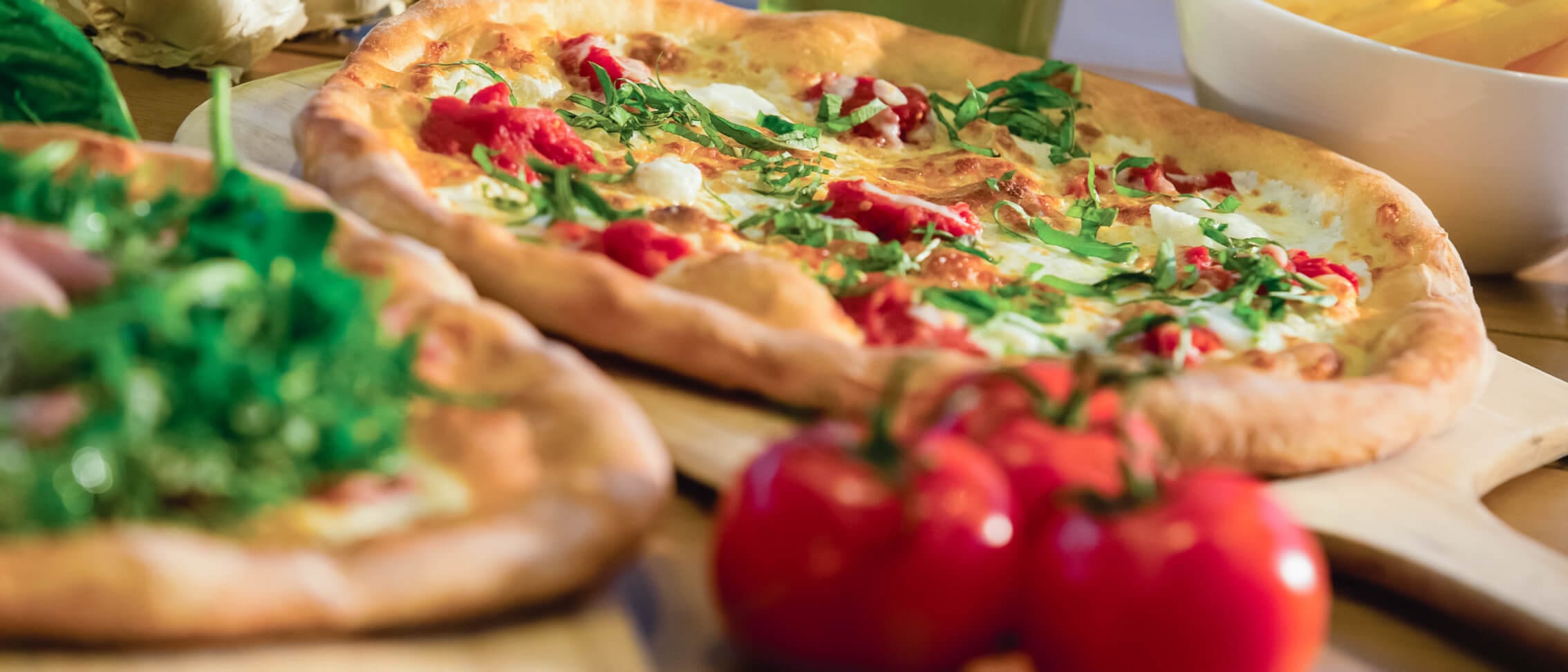 A fresh pizza topped with tomatoes, mozzarella, and chopped basil at the Red Oven Pizza Bakery.