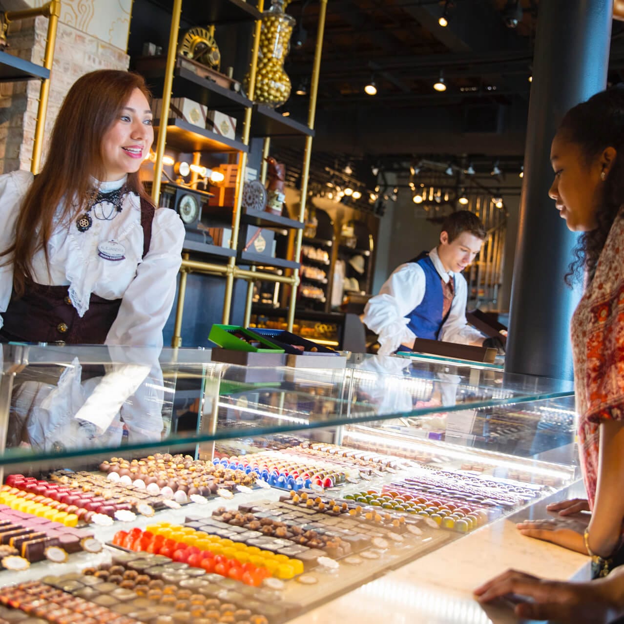 A woman looks at a display case full of artisanal chocolates at Toothsome Chocolate Emporium and Savory Feast Kitchen, a full service restaurant that also features a candy shop and dessert bar at Universal CityWalk Orlando.