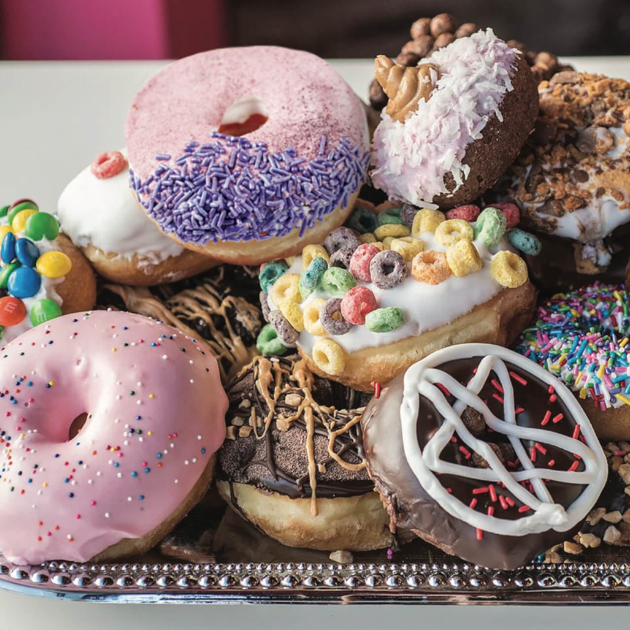 A tray piled high with an assortment of colorful and unique doughnuts from Voodoo Dougnut.