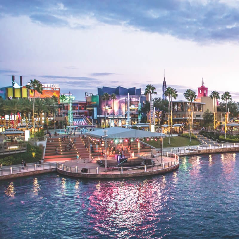 A water taxi cruises along the lagoon in front of a panoramic view of the restaurants, shops and nightclubs of the Universal CityWalk entertainment complex.