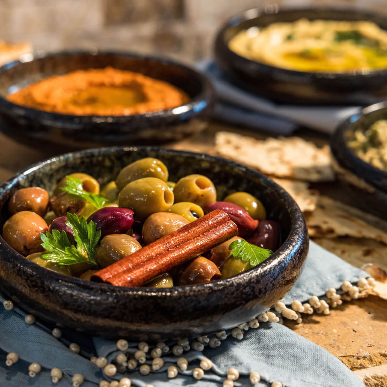 Mezzes & Spreads assortment of baba ghanoush, marinated olives, hummus, tzatziki, whipped summer feta and roasted red pepper dip, served with warm focaccia, pita and lavash at Flora Taverna.