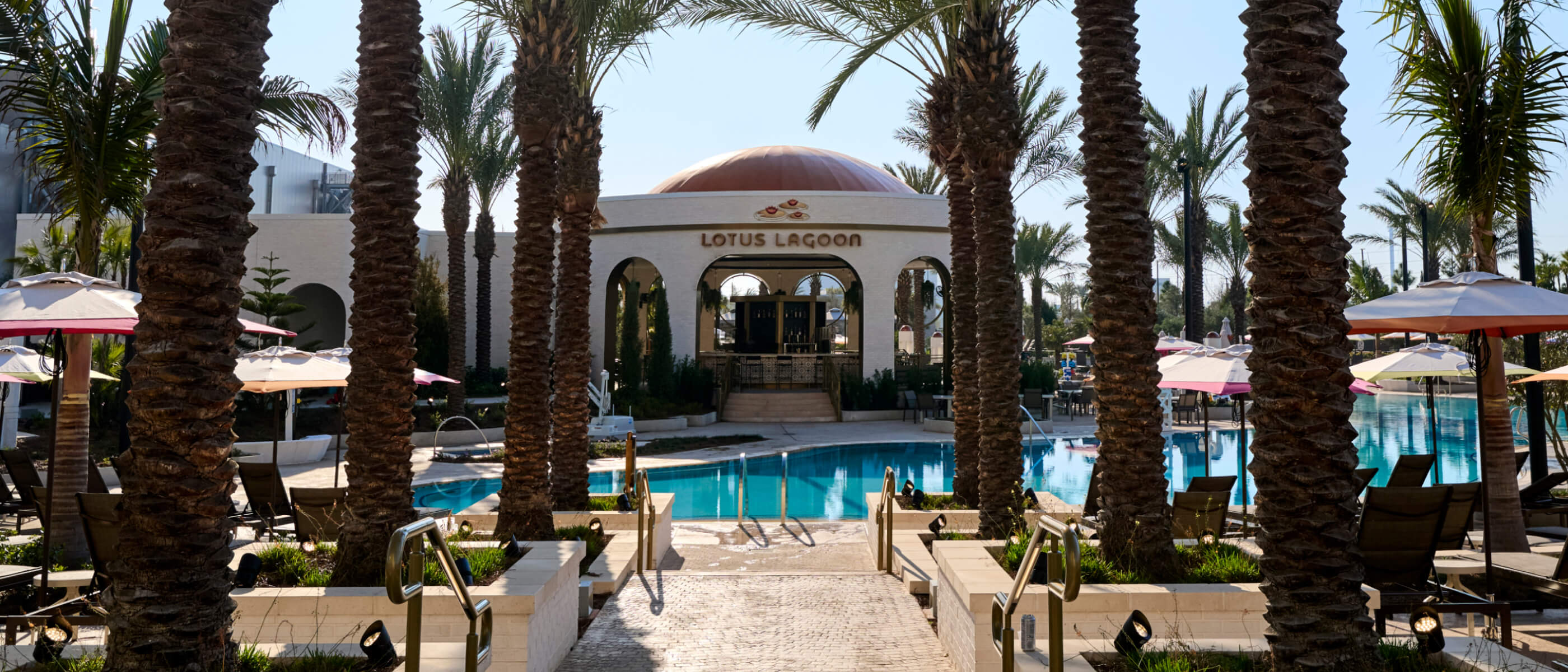 Palm tree-lined walkway to the pool and Lotus Lagoon open-air restaurant at Universal Helios Grand Hotel.