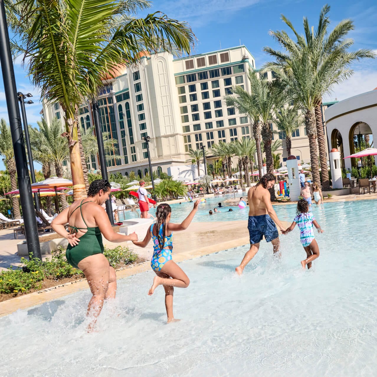 A young family splashing into the zero-entry pool at Universal Helios Grand Hotel, a Loews Hotel.