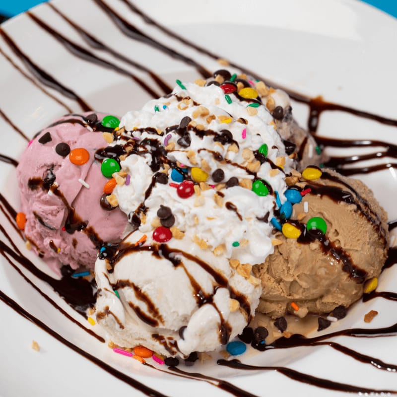 A four scoop, ice cream sundae with chocolate drizzle and candy toppings on a plate from Emack & Bolio’s at Hard Rock Hotel Orlando.