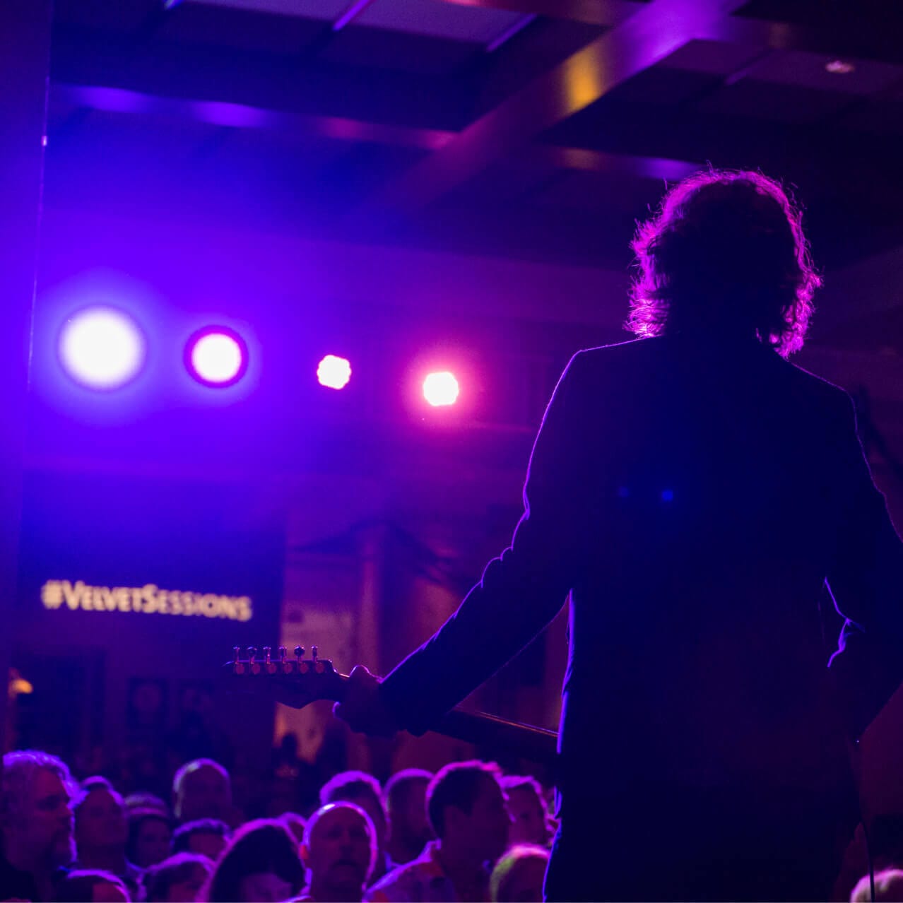 The silhouette of a man holding a guitar looking out into the audience at Velvet Sessions, a close up concert series at Hard Rock Hotel in Universal Orlando.