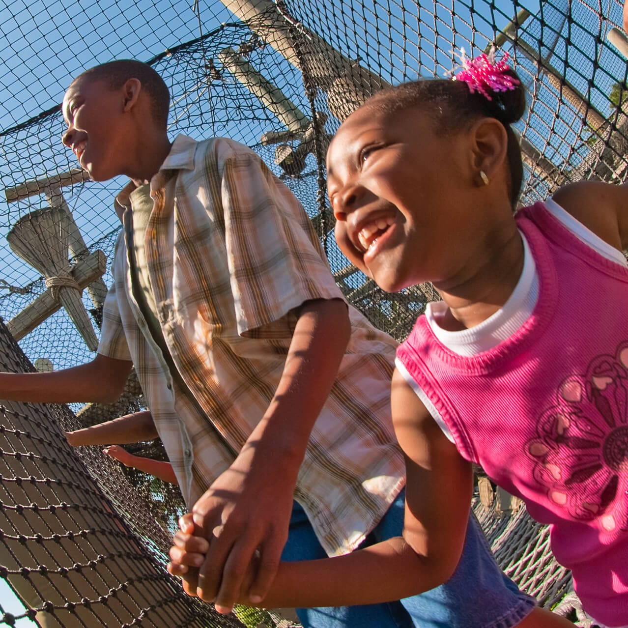 A girl and dad climb through a netted play area at Camp Jurassic in Islands of Adventure.