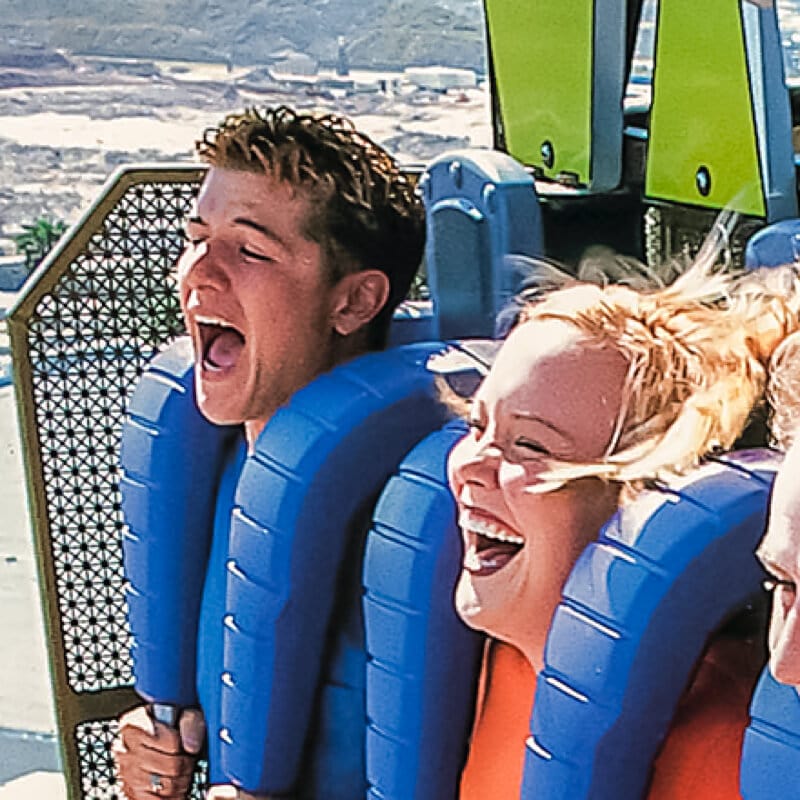A close up of two guests smiling and screaming as they face the drop