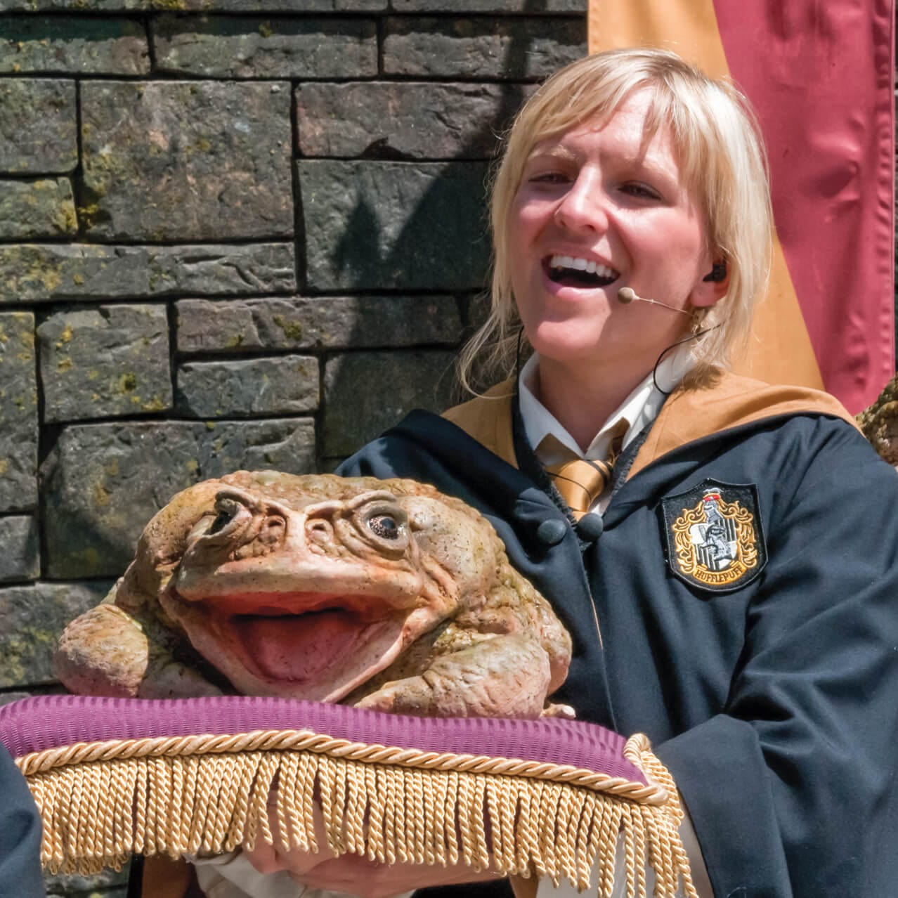 An enthusiastic Frog Choir singer holding her musical frog during a performance at The Wizarding World of Harry Potter Hogsmeade at Universal's Islands of Adventure in Orlando.