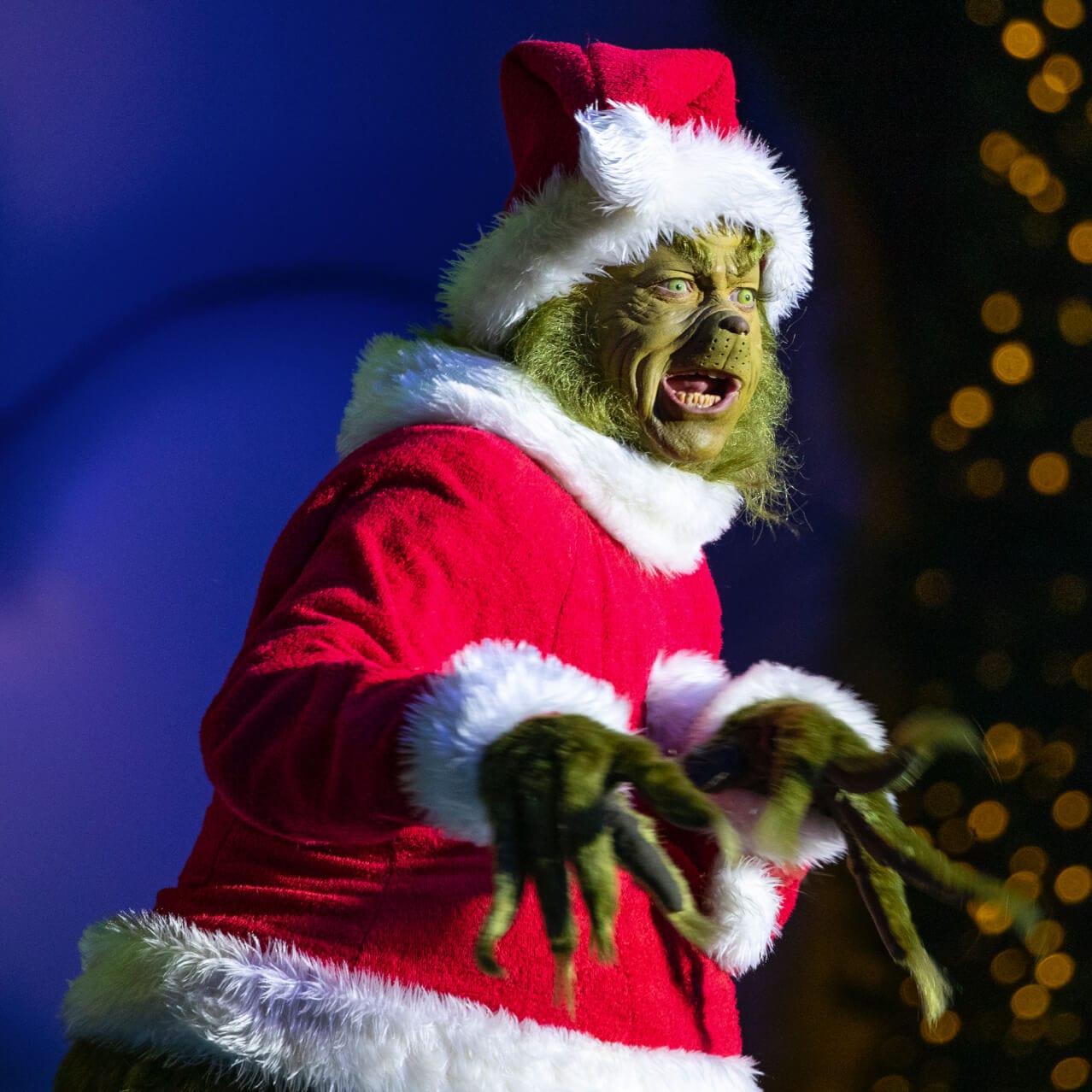 The Grinch wearing a Santa suit slinks around onstage during a live show at Universal’s Islands of Adventure.