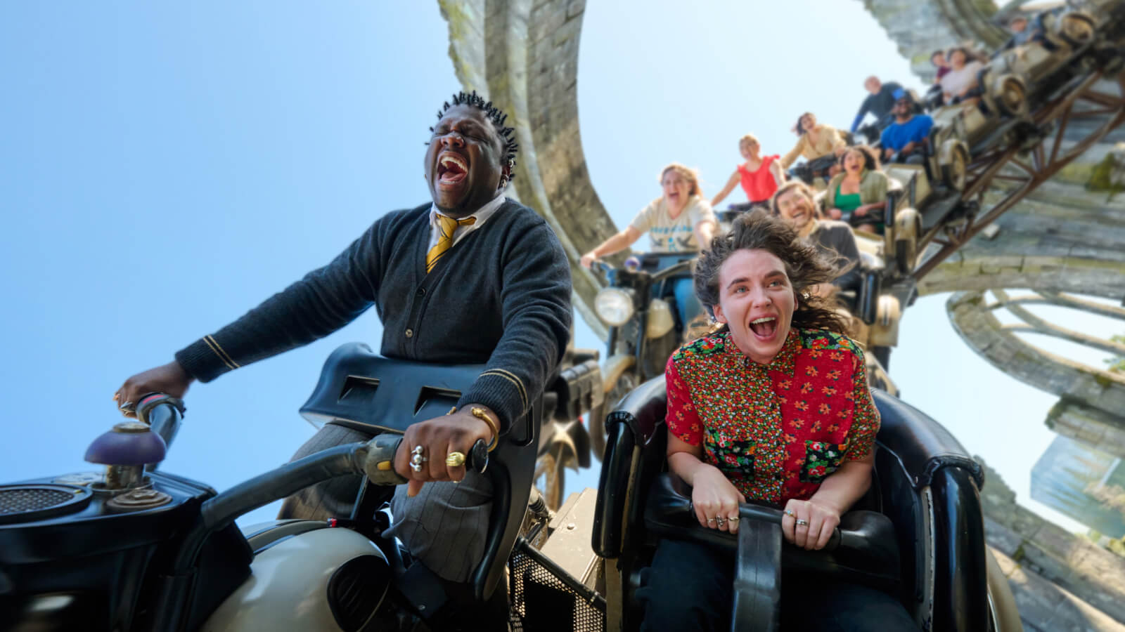 Guests screaming in delight while gripping the handlebars of their motorcycle-style vehicles as they hurtle through the air.