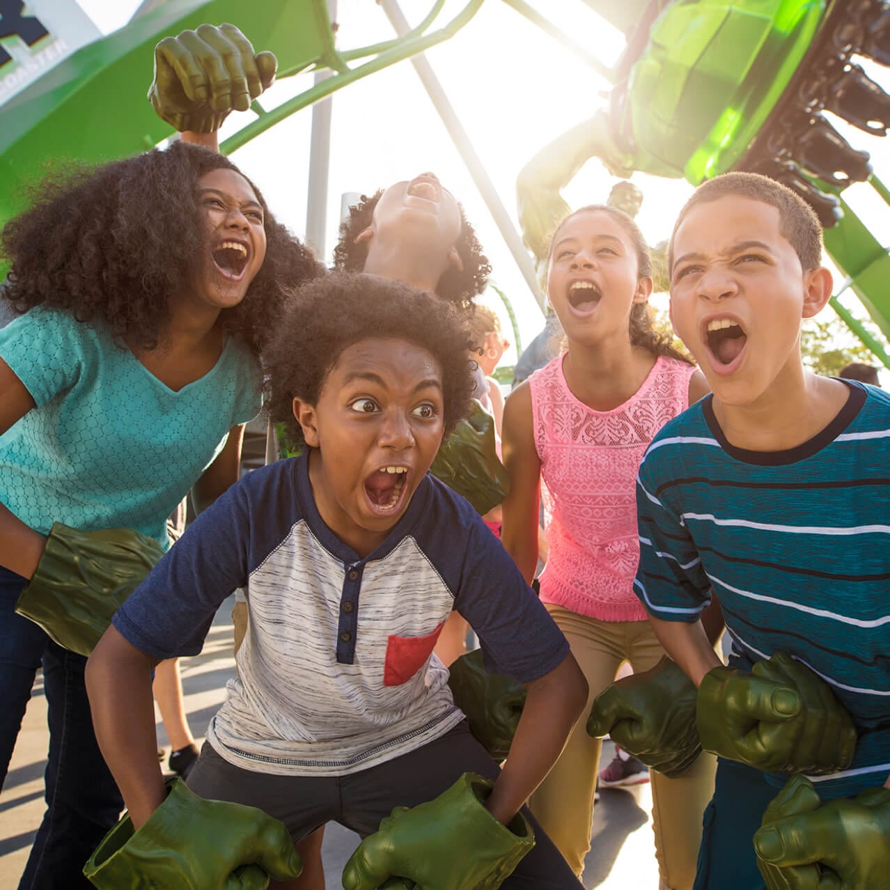 Five children perform their best Hulk impressions while wearing Hulk hand gloves in front of the queue for The Incredible Hulk Coaster at Universal's Islands of Adventure in Orlando.