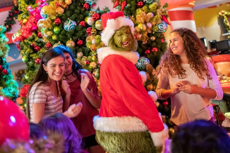 Guests meet and laugh with the Grinch dressed in a Santa costume during the holidays at Universal.