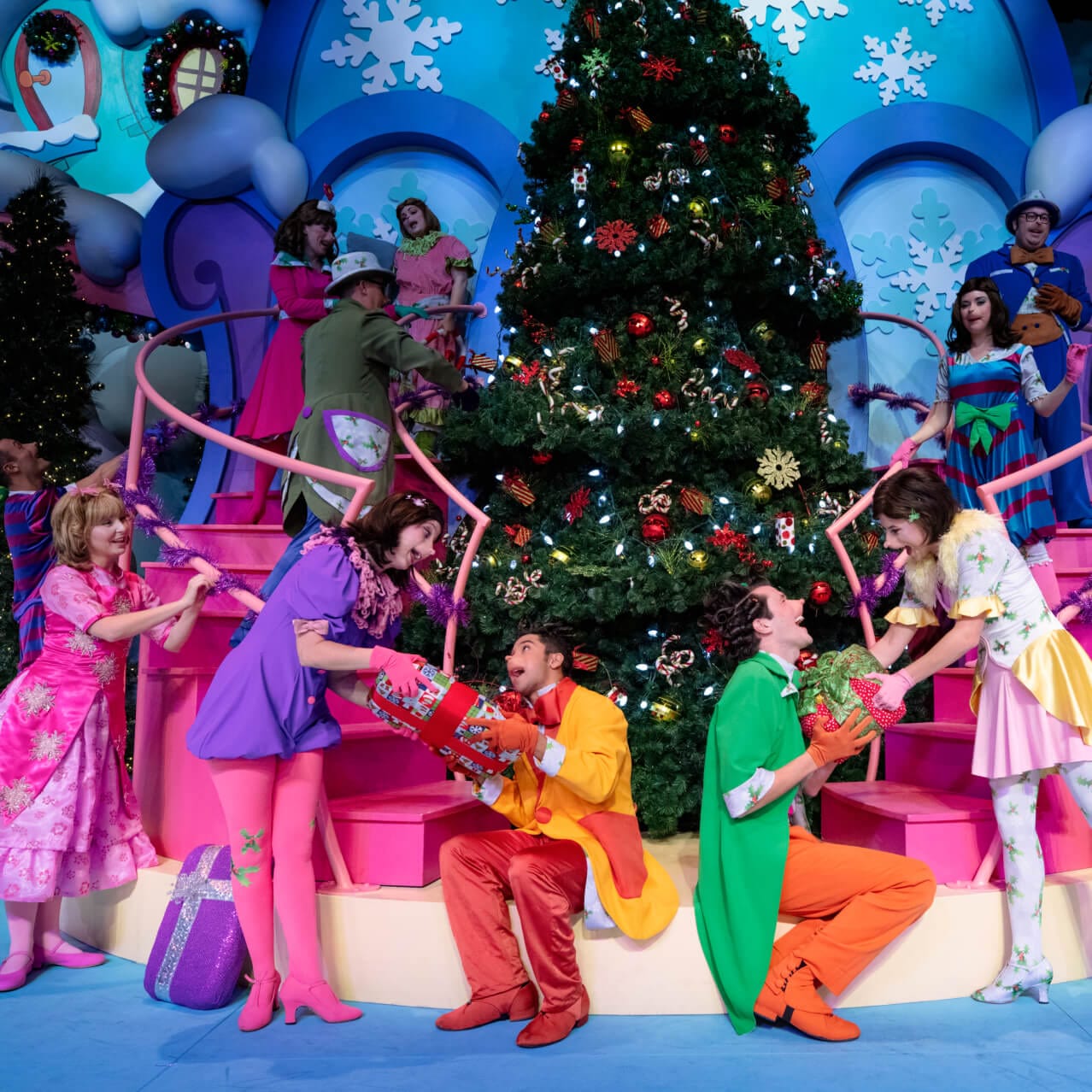 A happy Cindy Lou and Whos in Who-ville passing gifts around Christmas tree at Universal Orlando's Grinchmas Who-liday Spectacular.