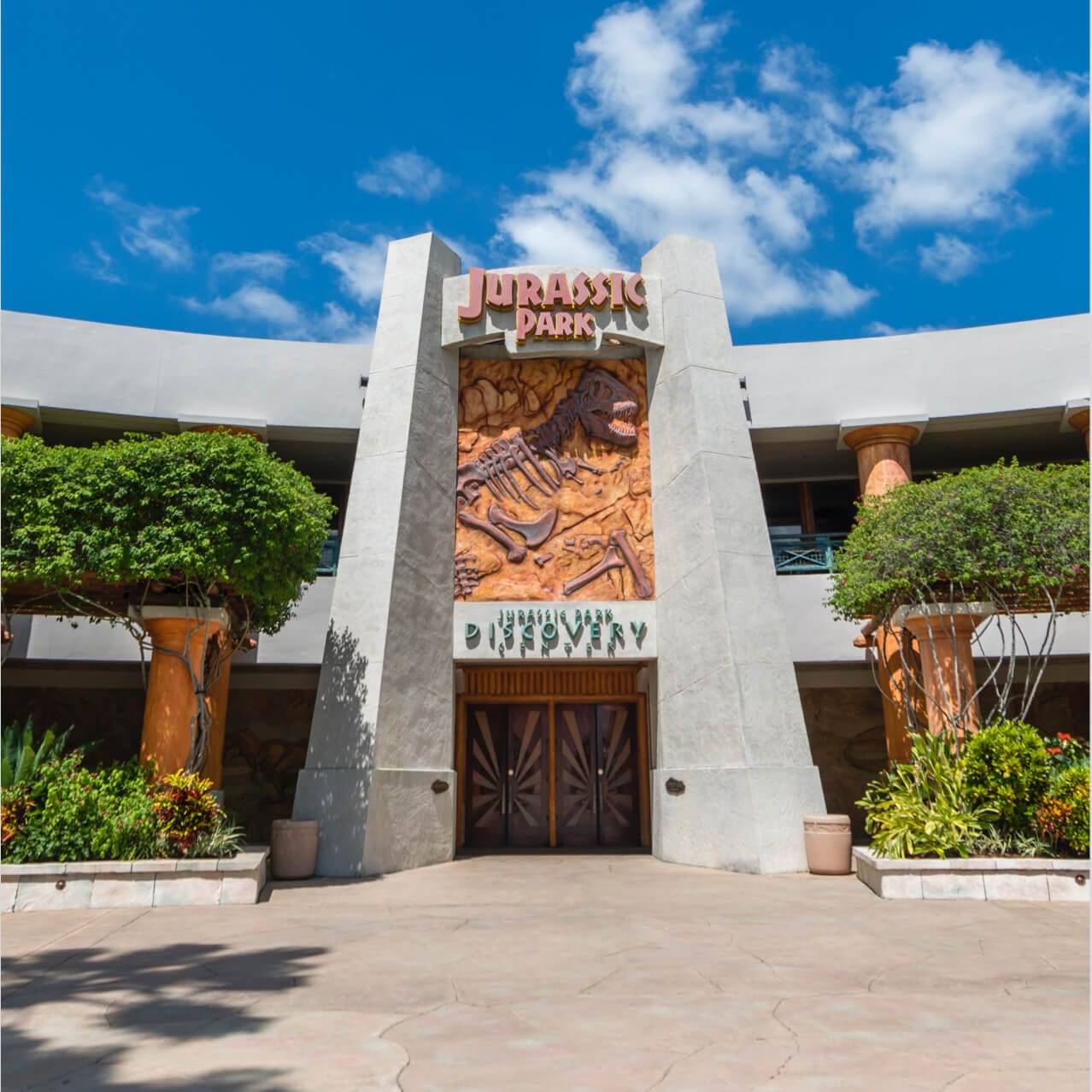 The impressive, palm tree lined entrance to the Jurassic Park Discovery Center in Universal Orlando where you can learn about dinosaurs and our planet's prehistoric past.