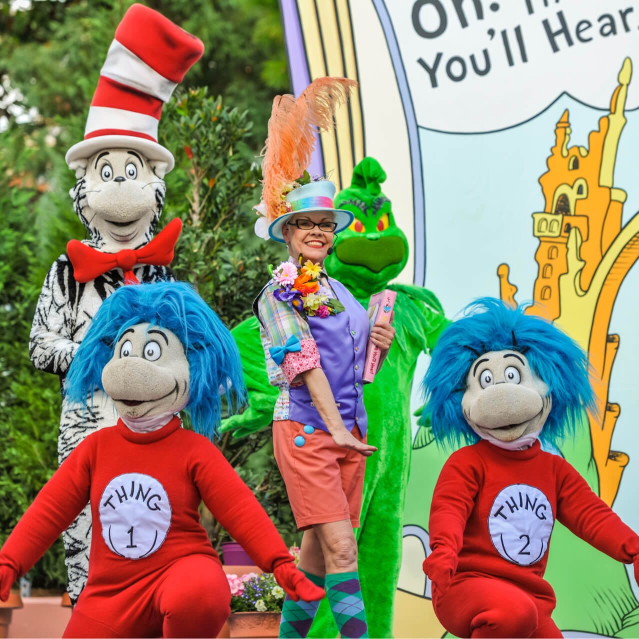 The storyteller from Oh! The Stories You'll Hear! in Seuss Landing at Universal Orlando poses alongside The Cat in the Hat, Thing One and Thing Two, and The Grinch.