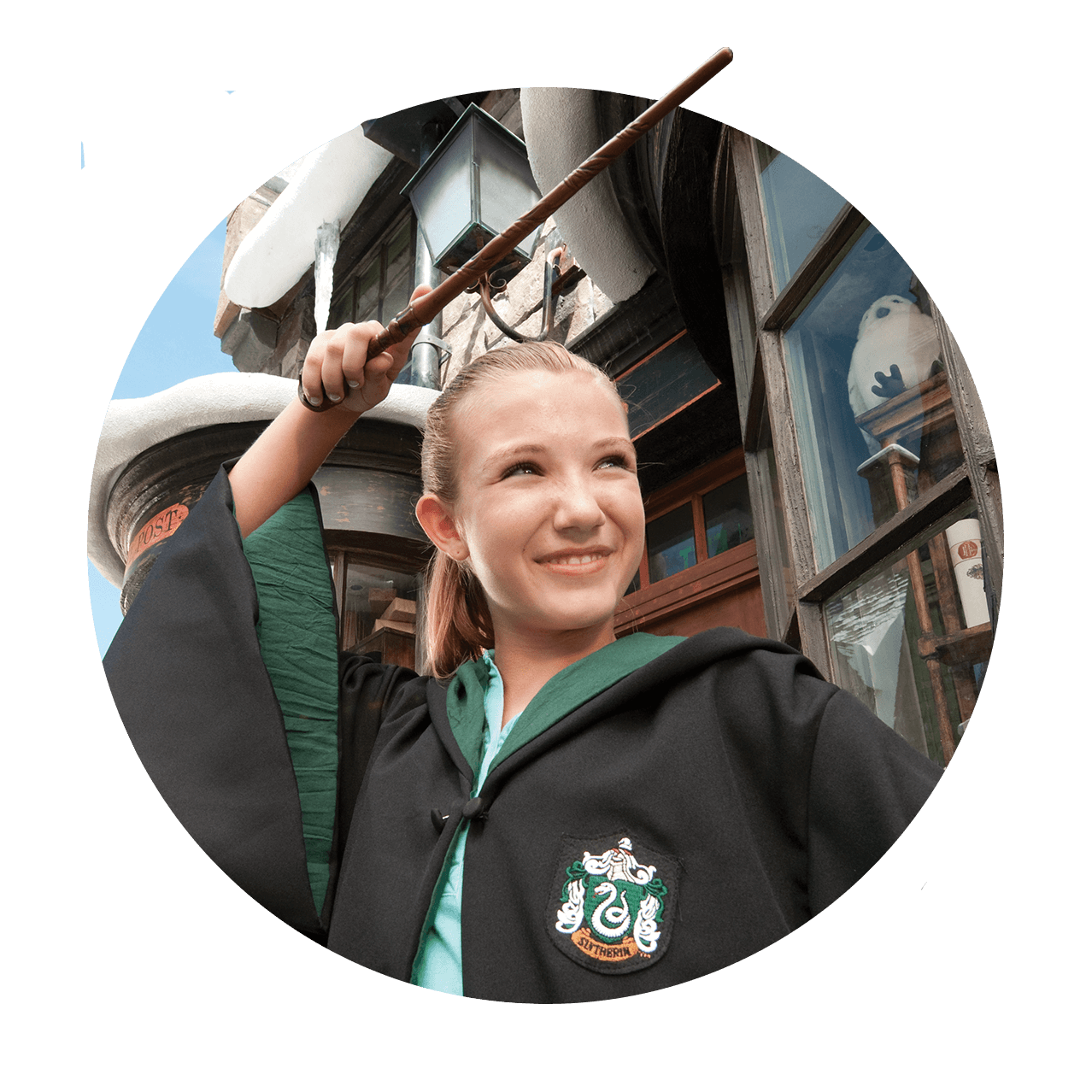 A little girl wearing Slytherin robes waves her wand as she casts a spell in The Wizarding World of Harry Potter Diagon Alley at Universal Studios Florida