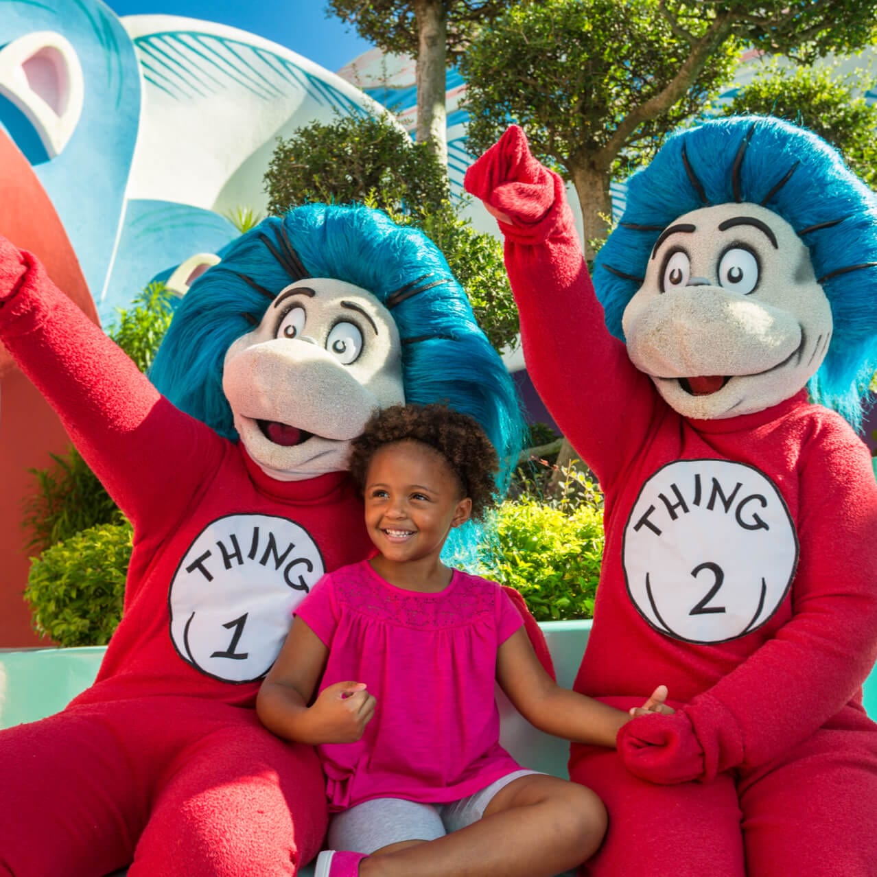 Dr. Seuss characters Thing One and Thing Two sit with a smiling young girl in the Seuss Landing area of Universal's Islands of Adventure.