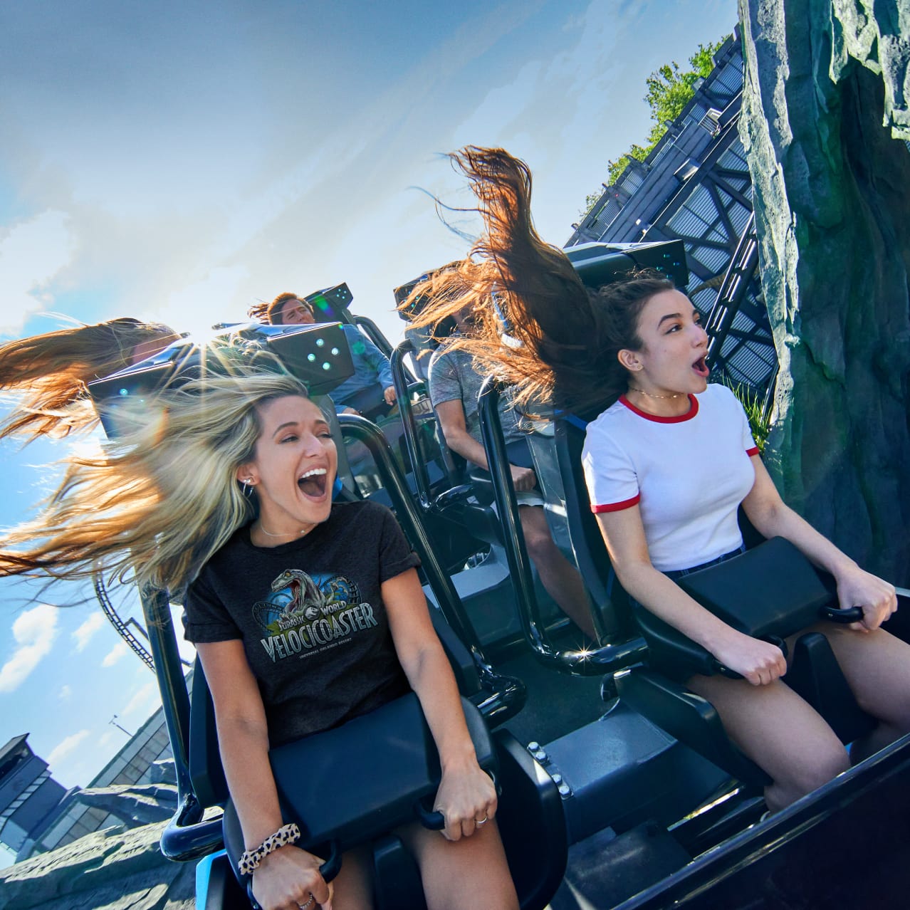 Two girls scream and smile as they grip the handles on the Velocicoaster ride at Universal Islands of Adventure.