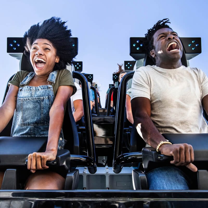 A couple screams and hangs on tight riding Jurassic World VelociCoaster.