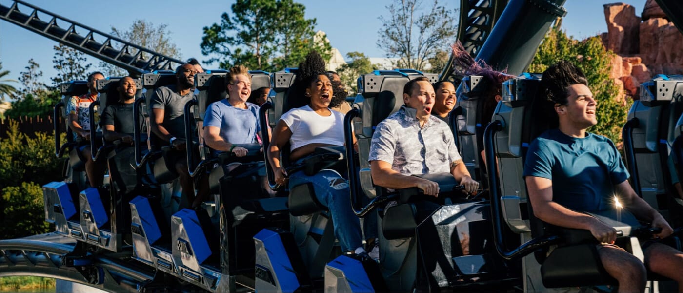 Right profile, close-up of thrilled riders zoom along the track on Jurassic World Velocicoaster.