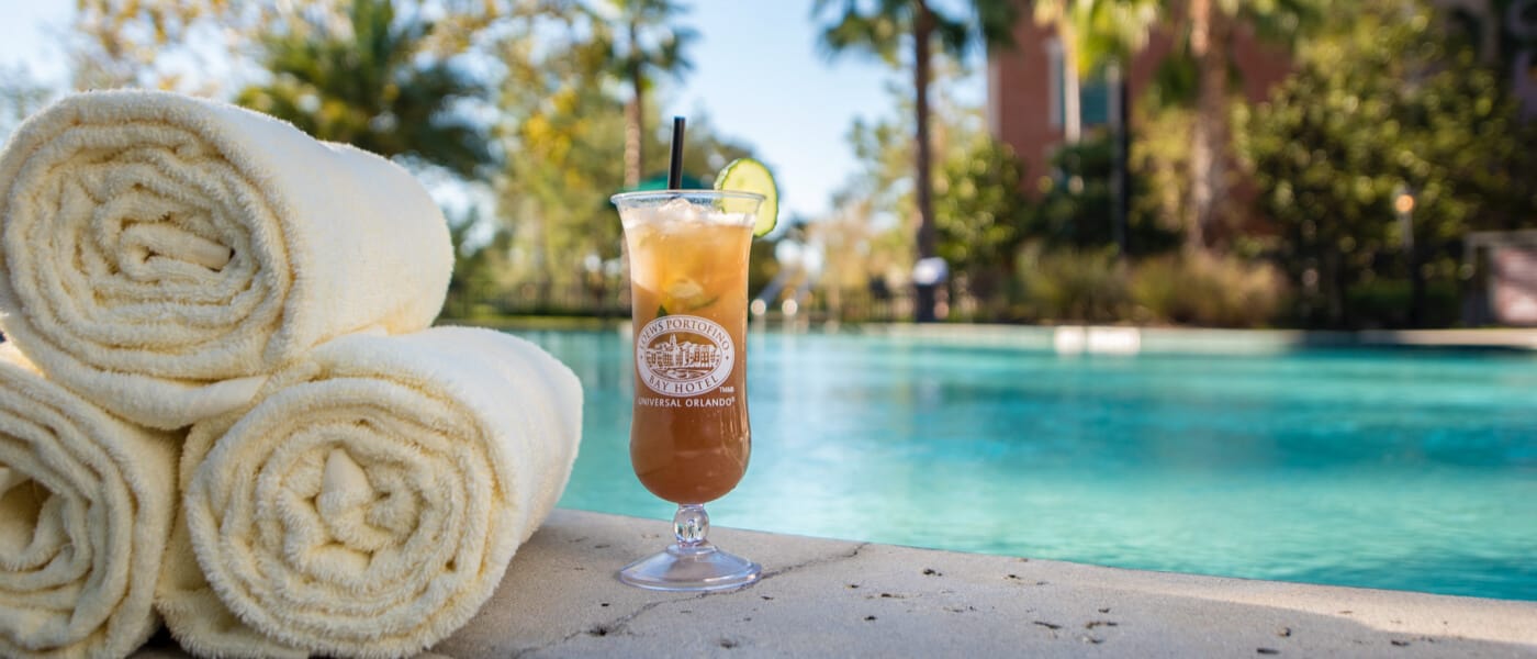 A cold drink and some rolled towels sit along the edge of a peaceful pool at Universal Orlando's Lowes Portofino Bay Hotel.