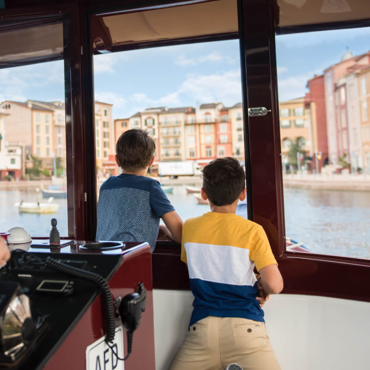 Two boys look out the front of a Universal Orlando water taxi as it approaches Loews Portofino Bay Hotel.