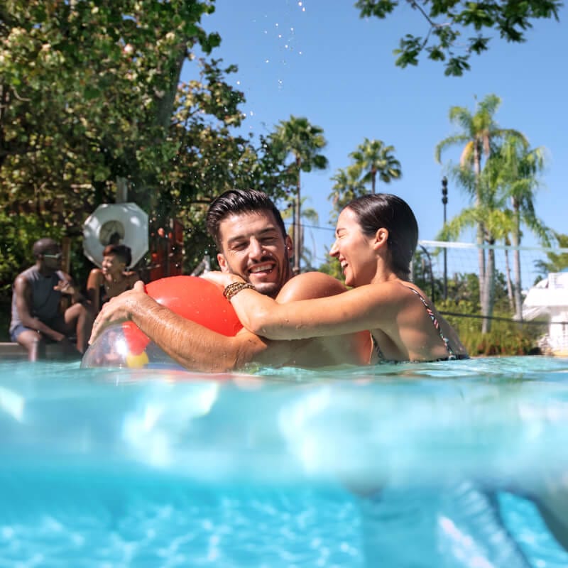 Two guests playing with an inflatable pool toy in the water at Loews Royal Pacific Resort.