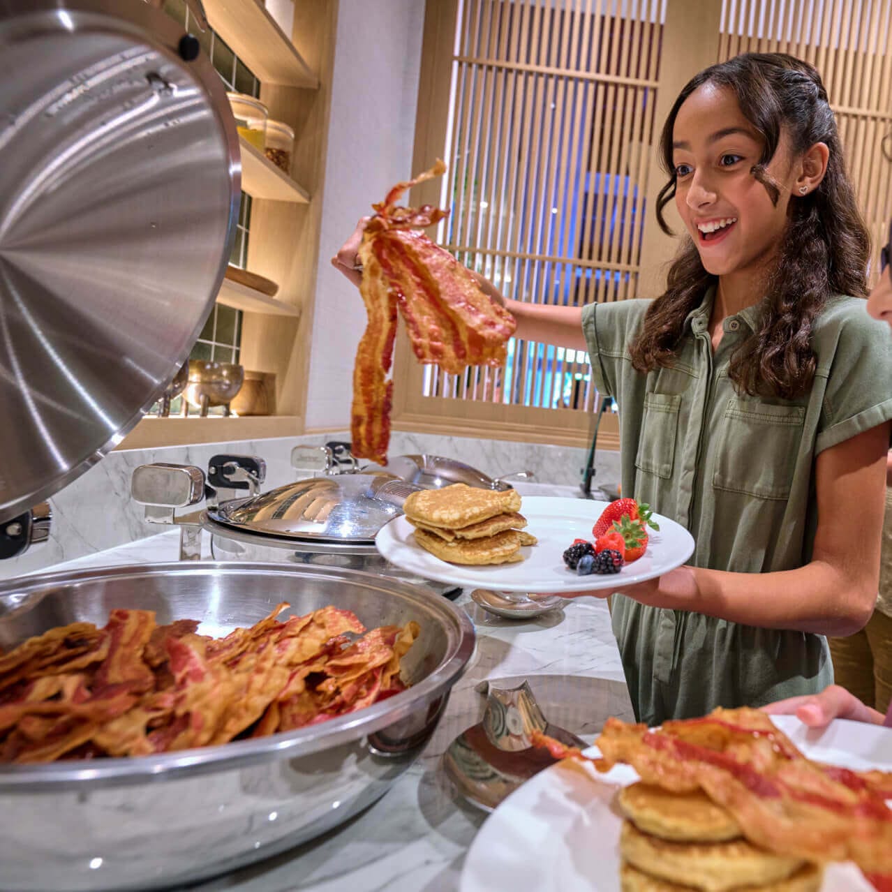 Kids getting bacon at the buffet table at Islands Dining Room in Loews Royal Pacific Resort.