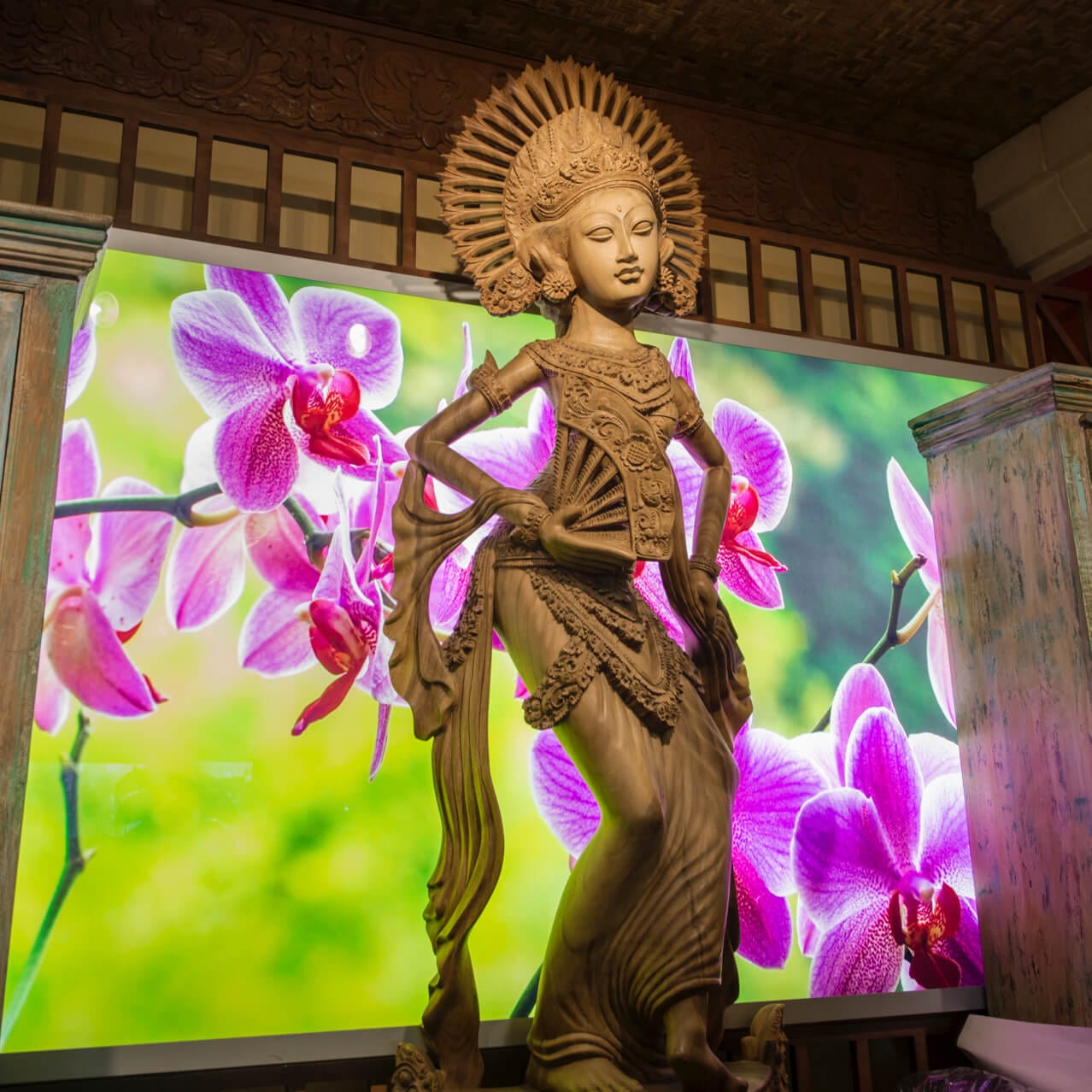 An intricate Polynesian inspired statue in front of vibrant orchid artwork inside Loews Royal Pacific Resort.