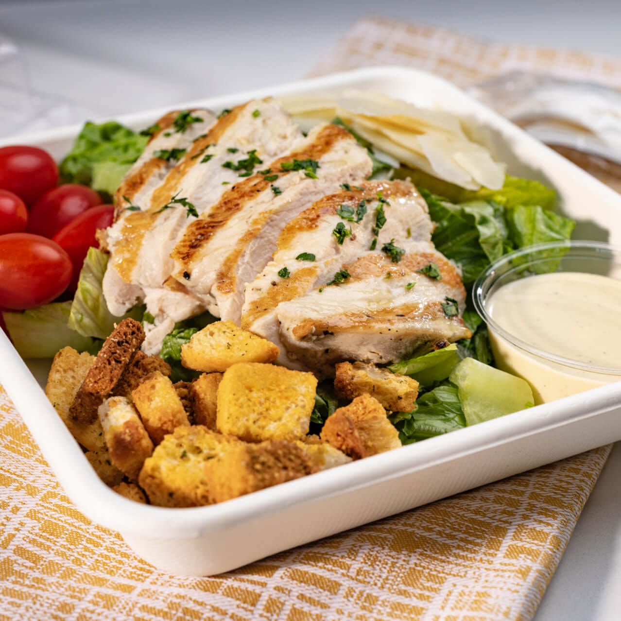 Garden salad with grilled chicken and dressing in a salad bowl.