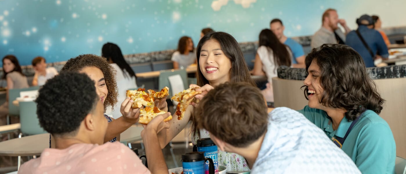 Five friends enjoying food and drinks inside of the Cosmos Cafe and Market at Universal Stella Nova Resort.
