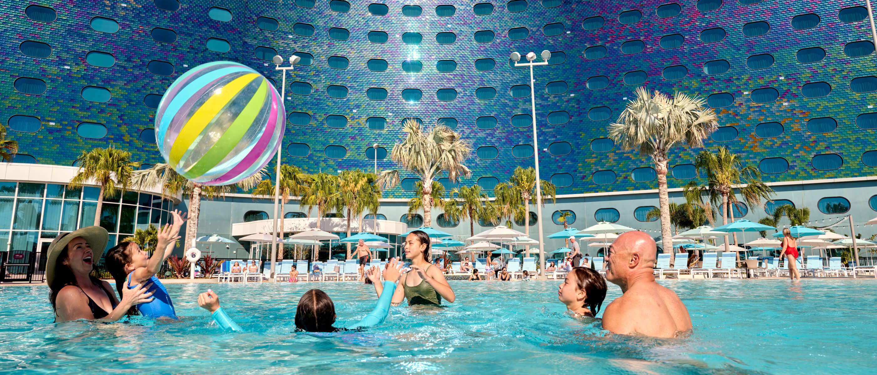 A young family of six play with a giant beach ball in the pool at Universal Terra Luna Resort.