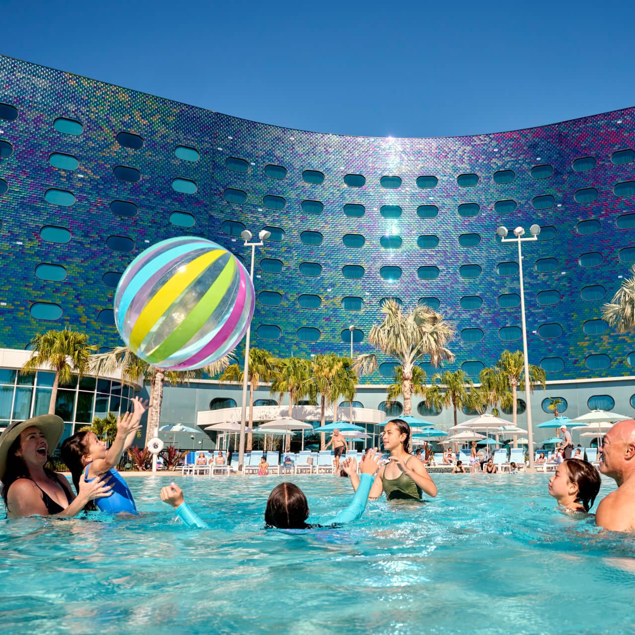 A young family of six play with a giant beach ball in the pool at Universal Terra Luna Resort.