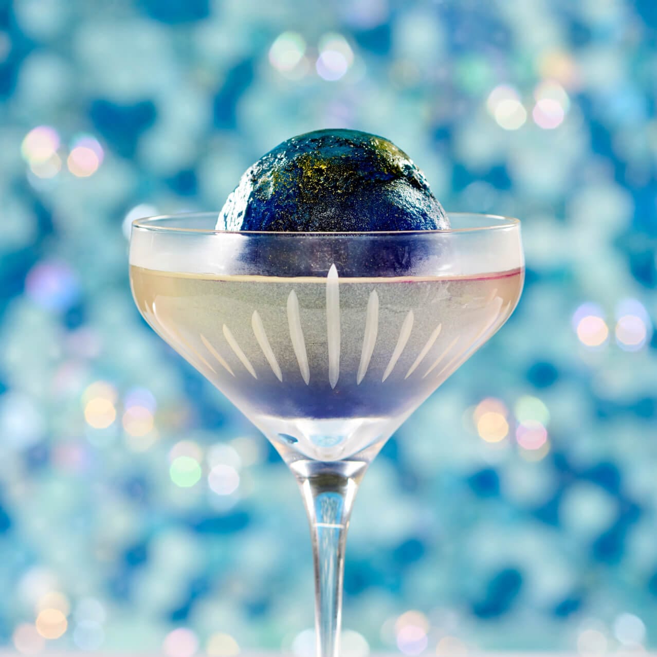 Northern Lights Martini with a garnish of butterfly pea blossom ice sphere, served at Atlantic in Celestial Park.