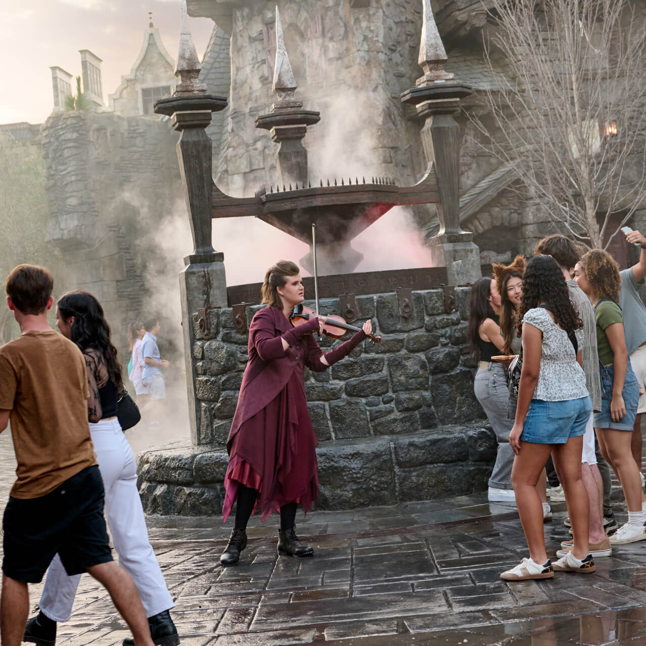 A street performer plays her violin for guests of Darkmoor Village in Dark Universe.