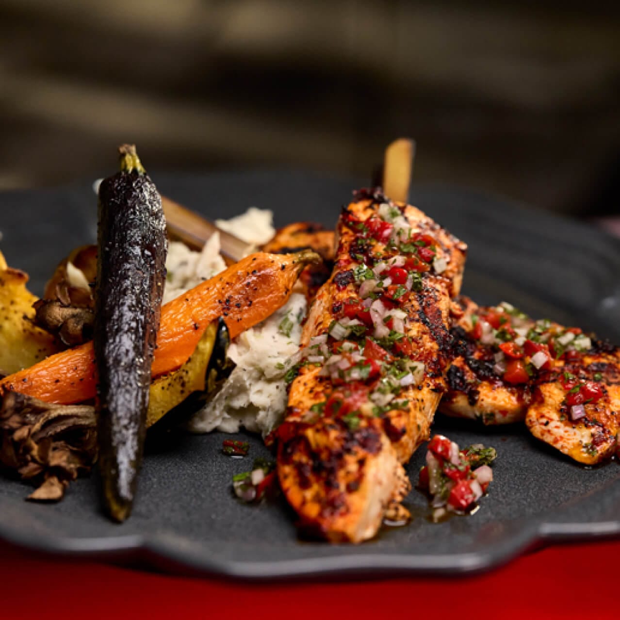 Bird on a Stake, a dish of grilled chicken tenderloin with red chimichurri, charred green onion mashed potatoes and roasted vegetables served at Das Stakehaus in Dark Universe.
